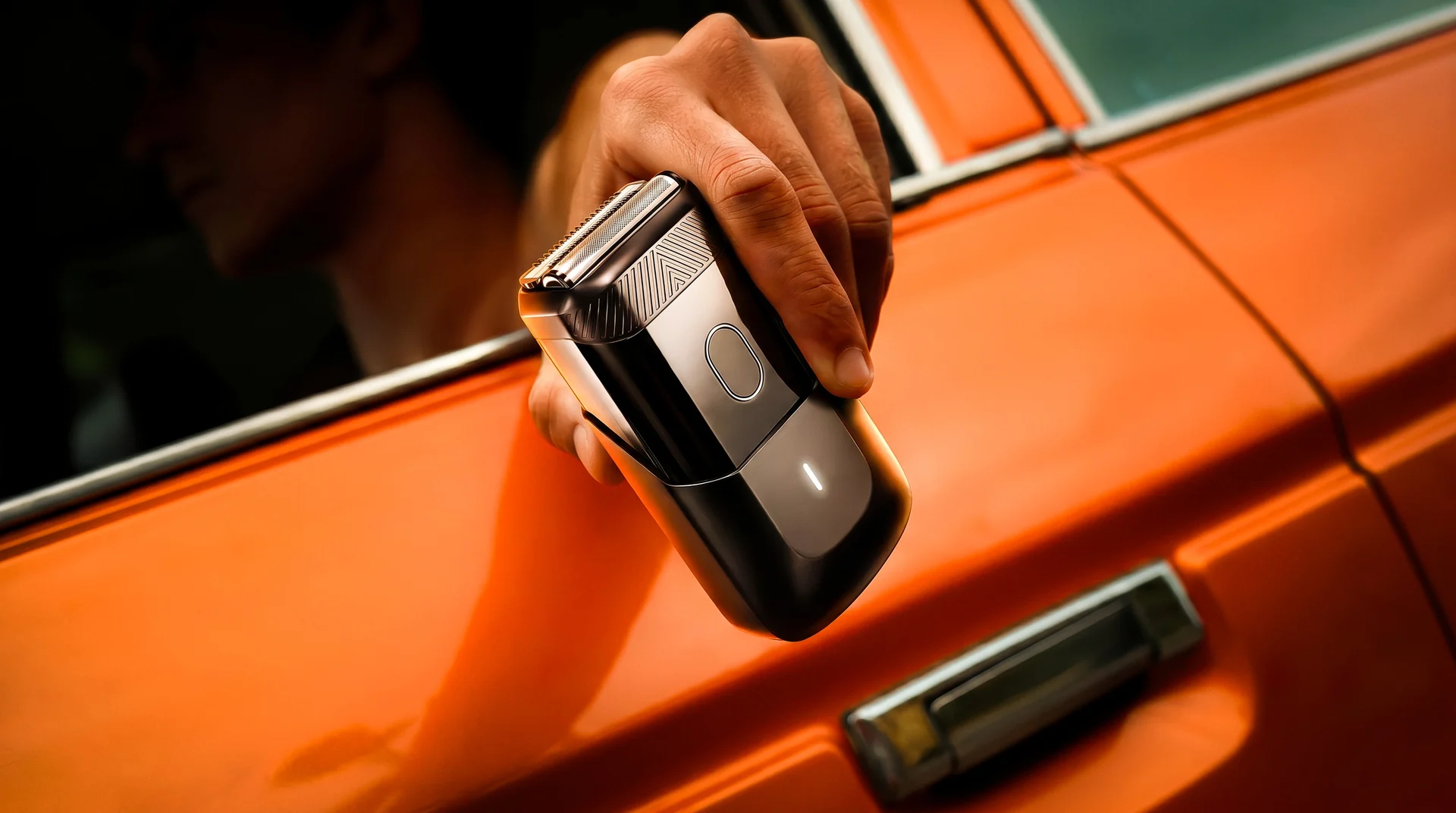 Mão segurando o barbeador na janela de um carro laranja