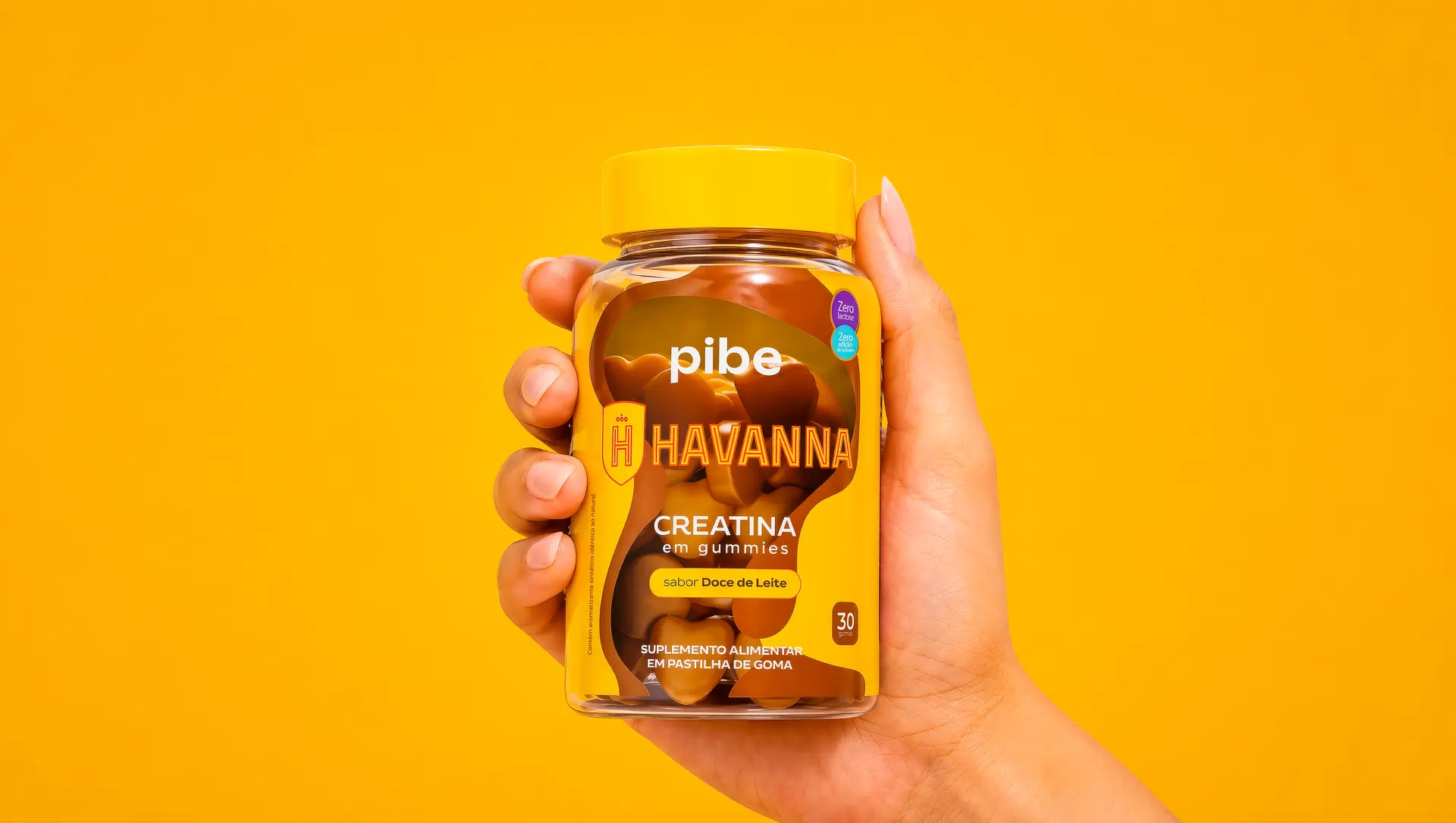 Mão segurando o pote de creatina Pibe × Havanna